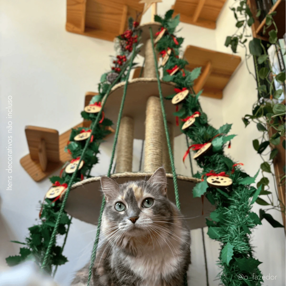 Árvore para gatos decorativa com arranjos festivos e uma gata em primeiro plano.